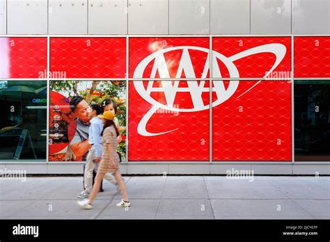 An Asian Couple Walks Past A Large Aaa Logo Outside The American An Asian Couple Walks Past A Large Aaa Logo Outside The American